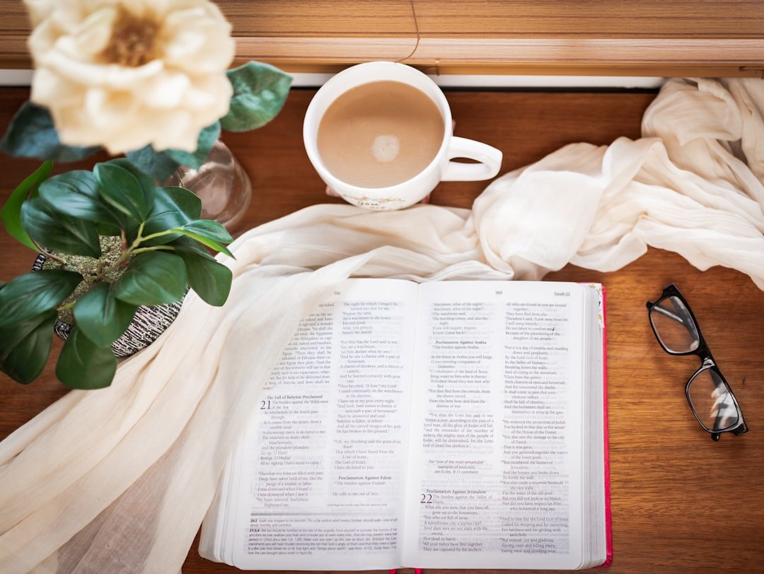 Flat lay of a journal, plant and coffee cup on a wooden desk